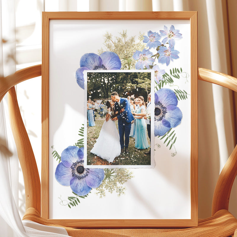 Cadre de préservation de bouquet de mariée avec une véritable photographie centrale des mariés, entourée d'anémones bleues, de delphinium et d'autres fleurs pressées (Formule Hortensia).