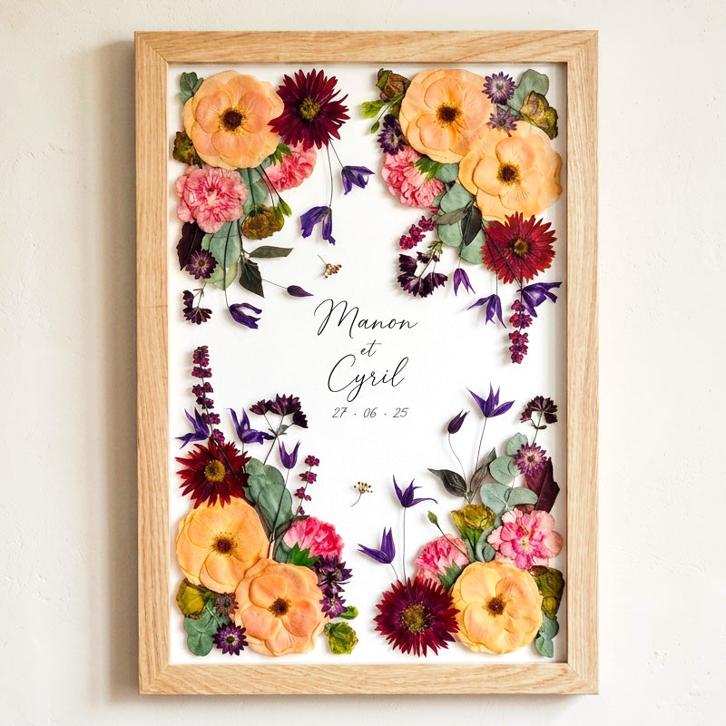 adre en bois clair avec la préservation d'un bouquet de mariée aux tons orangés et bordeaux, encadrant les prénoms Manon et Cyril avec la date du mariage écrits à la main par Wild Poppy (Formule Marguerite).